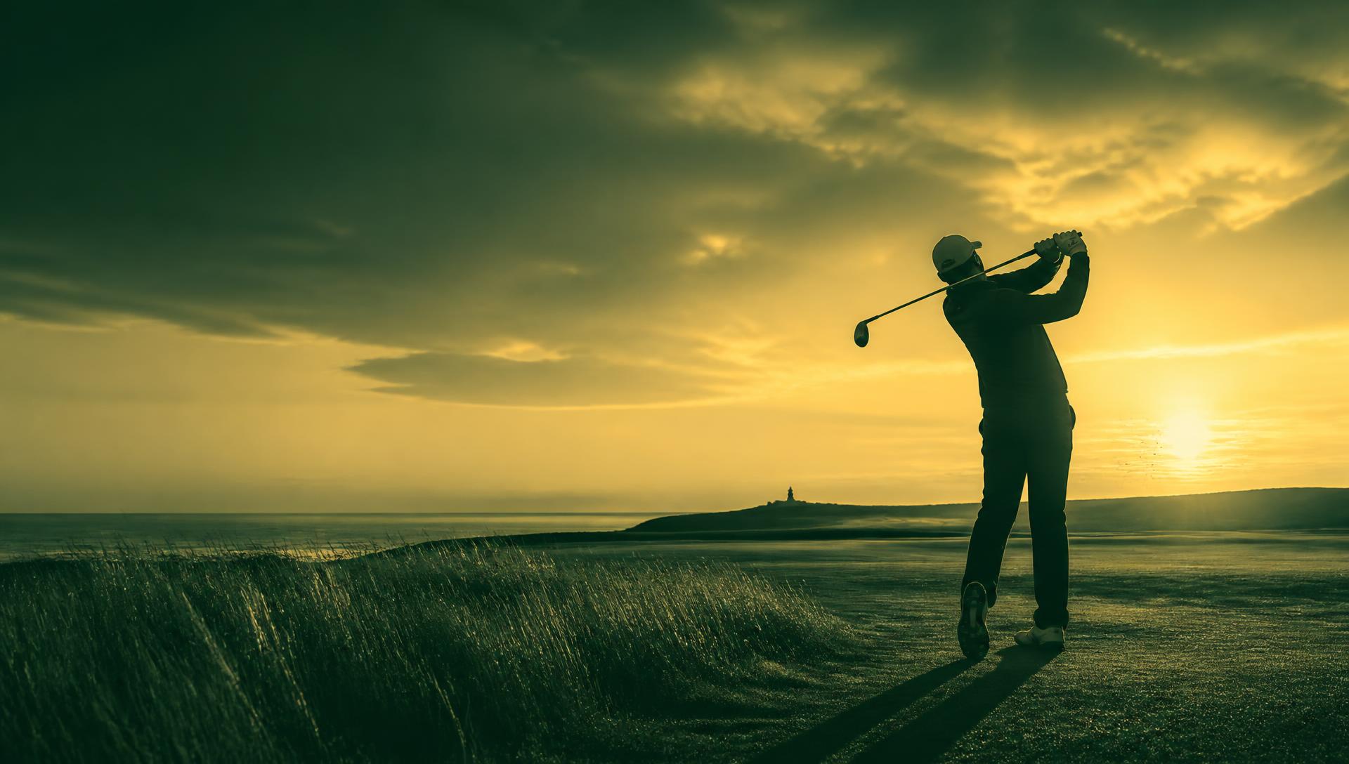 Golfer completing a swing at sunrise on a coastal links course